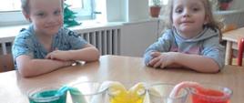 Dzieci pozują przed kubkami wypełnionymi kolorową cieczą