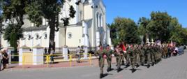 Kompania reprezentacyjna 2. Brygady Pancernej Legionów z Czerwonego Boru maszeruje ulicą w Zambrowie podczas obchodów Święta Wojska Polskiego. W tle widoczny kościół pw. Trójcy Przenajświętszej.