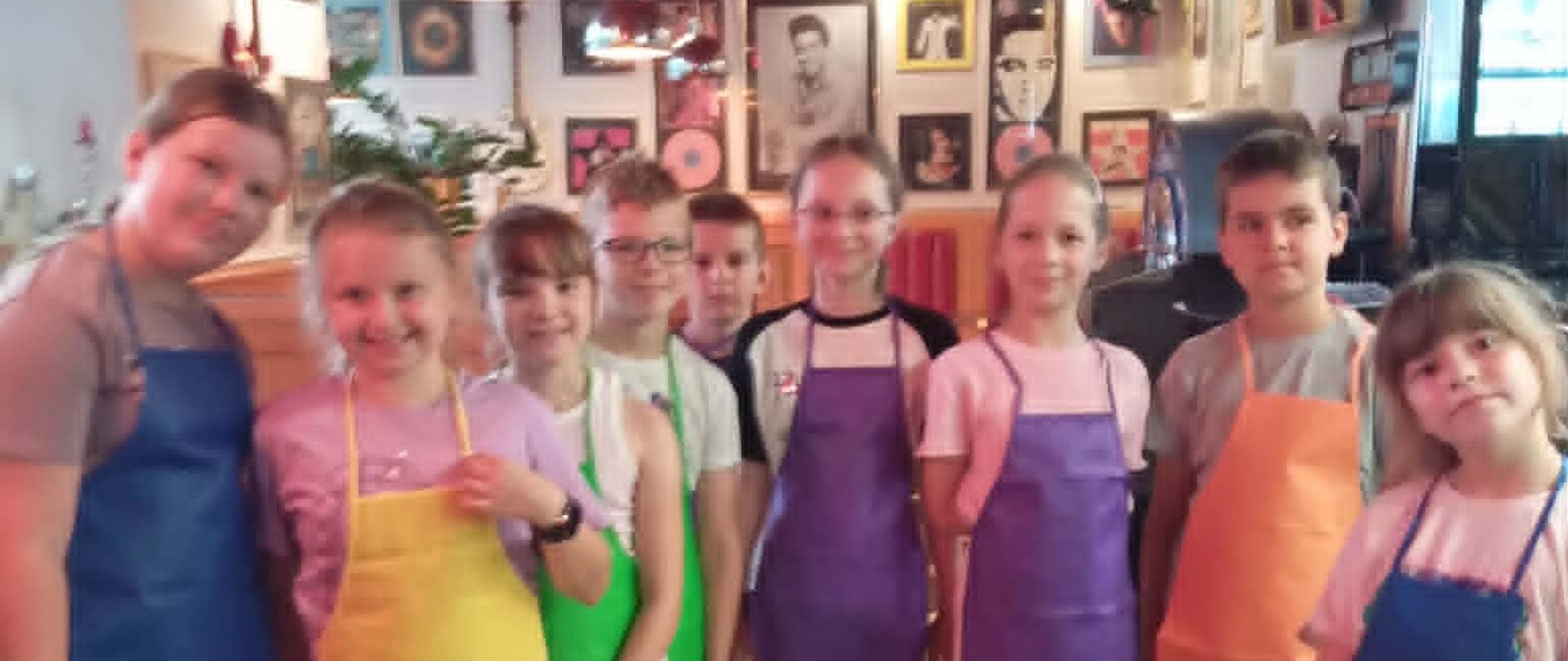 Uczniowie ubrani w fartuszki stoją w restauracji Rock'n'Roll