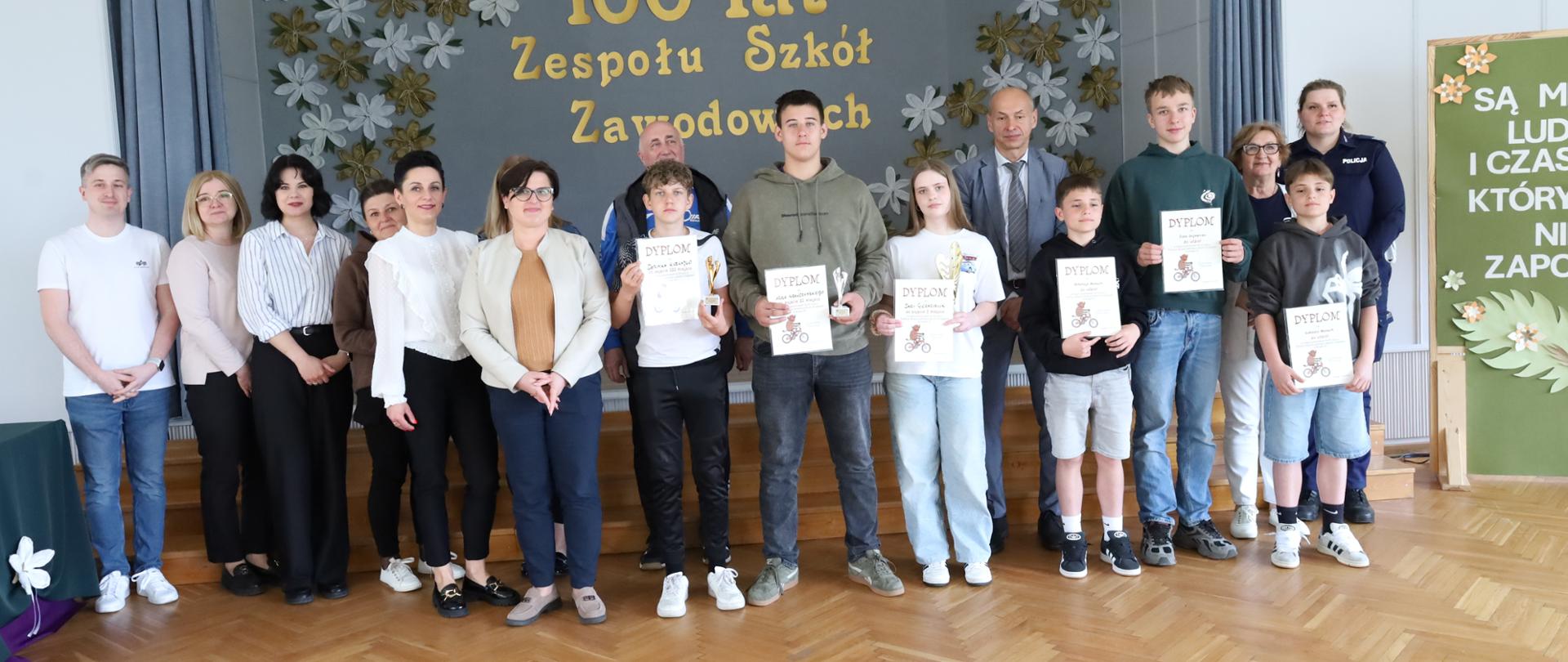 Uczestnicy turnieju z pucharami i dyplomami pozują do zdjęcia wraz z przedstawicielami organizatora