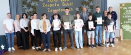 Uczestnicy turnieju z pucharami i dyplomami pozują do zdjęcia wraz z przedstawicielami organizatora