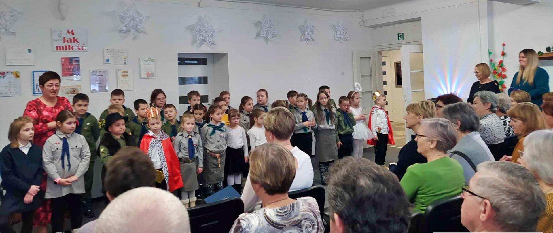 seniorzy podczas obchodów dnia babci i dziadka oglądają przedstawienie w wykonaniu dzieci