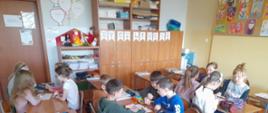 Dzieci siedzące w klasie przy ławkach