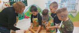 Wspólne pieczenie pierniczków - dzieci siedzą przy stole i wykonują czynności związane z przygotowaniem ciasteczek. Pozują przy tym do zdjęć