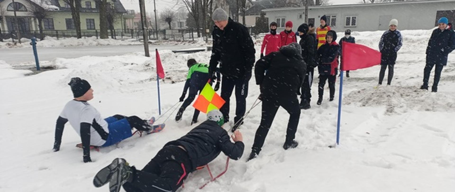Zabawy na śniegu - dzieci na korcie pokonują tor przeszkód