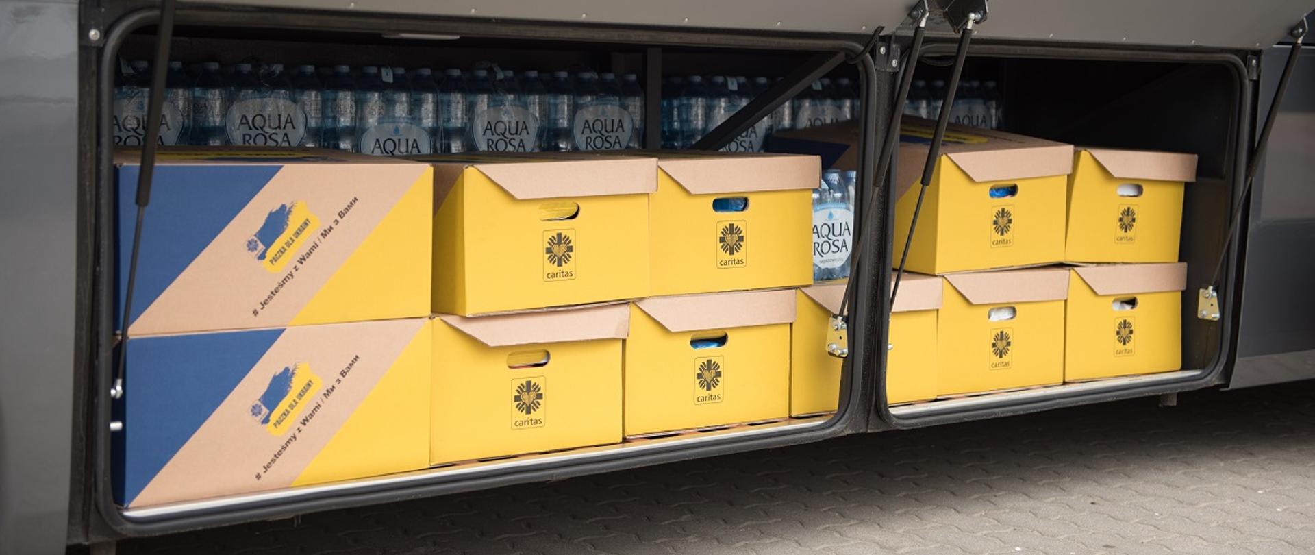 Na zdjęciu jeden z bagażników autobusu Zespołu Szkół Centrum Kształcenia Rolniczego w Sokołowie Podlaskim, do którego zapakowano wodę oraz żółto - niebieskie kartony z darami z logo Caritas przeznaczonymi dla ludności w Ukrainie