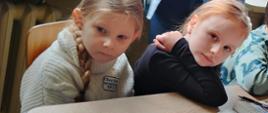 Dzieci siedzą w ławkach w sali lekcyjnej