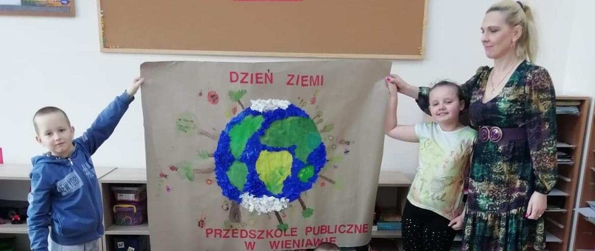 Zdjęcie grupy ,,Biedronki" wraz z nauczycielem. Dzieci trzymają plakat, który własnoręcznie namalowały.