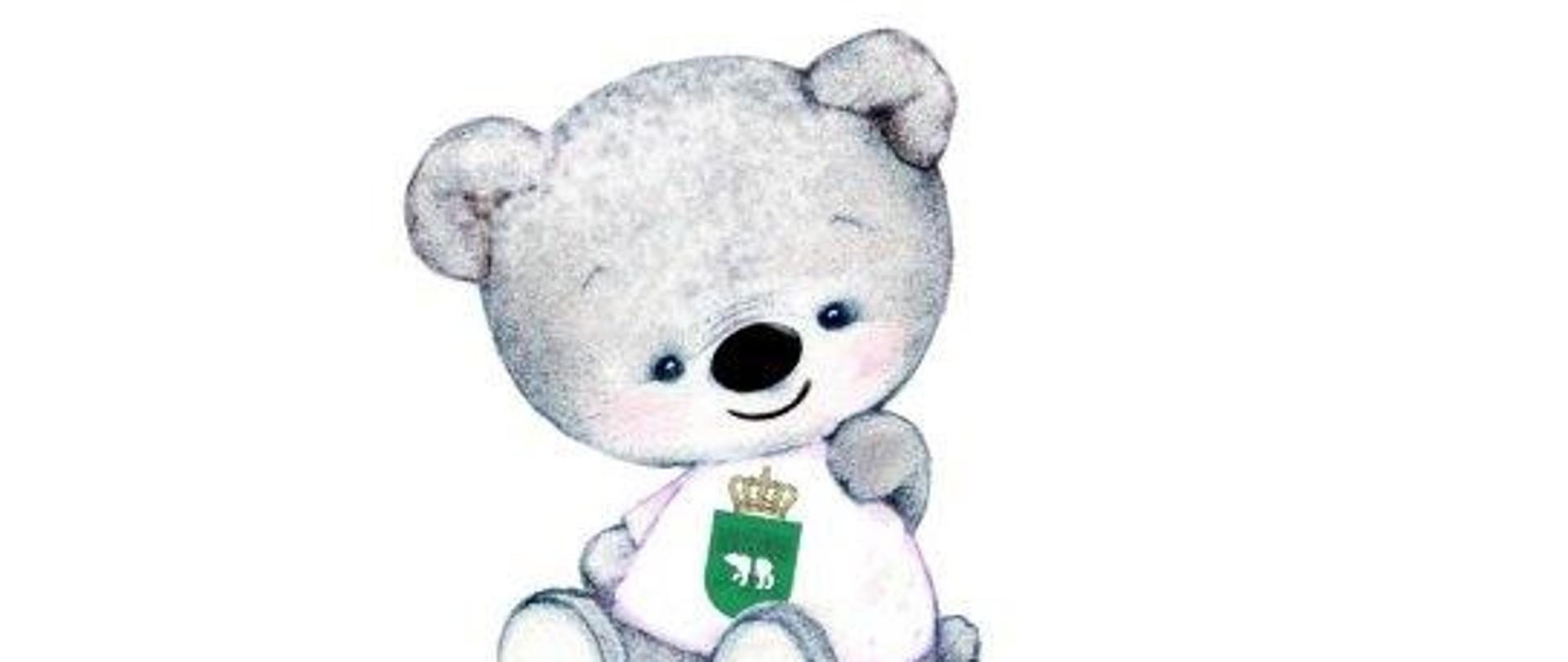 Zdjęcie przedstawia grafikę, na której widać pluszowego misia zabawkę (narysowanego), który ma na sobie śliniaczek z herbem Chełma (biały niedźwiedź na zielonym tle, nad herbem korona) i na dole napis "Jestem z Chełma".