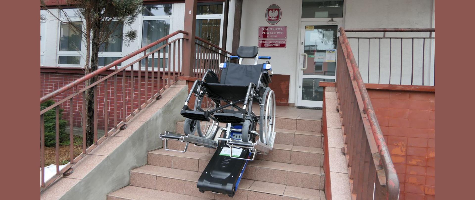 Prezentacja schodołazu wraz z wózkiem inwalidzkim na schodach prowadzących do Wydziału Komunikacji i Transportu Starostwa Powiatowego w Lipsku.