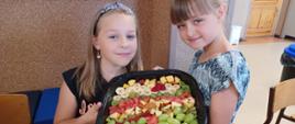 dziewczynki prezentują swoją sałatkę owocową