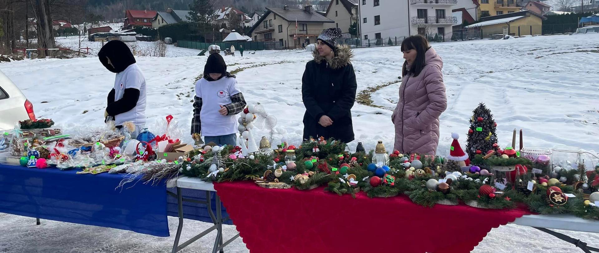 Wolontariusze Szkolnego Koła Wolontariatu sprzedają wykonane przez uczniów ozdoby świąteczne i stroiki oraz przygotowane przez rodziców ciasta
