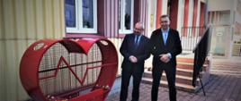 Stalowy pojemnik na nakrętki w kształcie serca stanął przy Powiatowym Centrum Pomocy Rodzinie w Powiecie Przasnyskim. Fotografia przedstawia stalowy pojemnik (po lewej) na nakrętki w kształcie serca z napisem Powiat Przasnyski oraz panów Starostę Przasnyskiego Krzysztofa Bieńkowskiego (po lewej) oraz Dyrektora Powiatowego Centrum Pomocy Rodzinie Krzysztofa Gosia (po prawej).