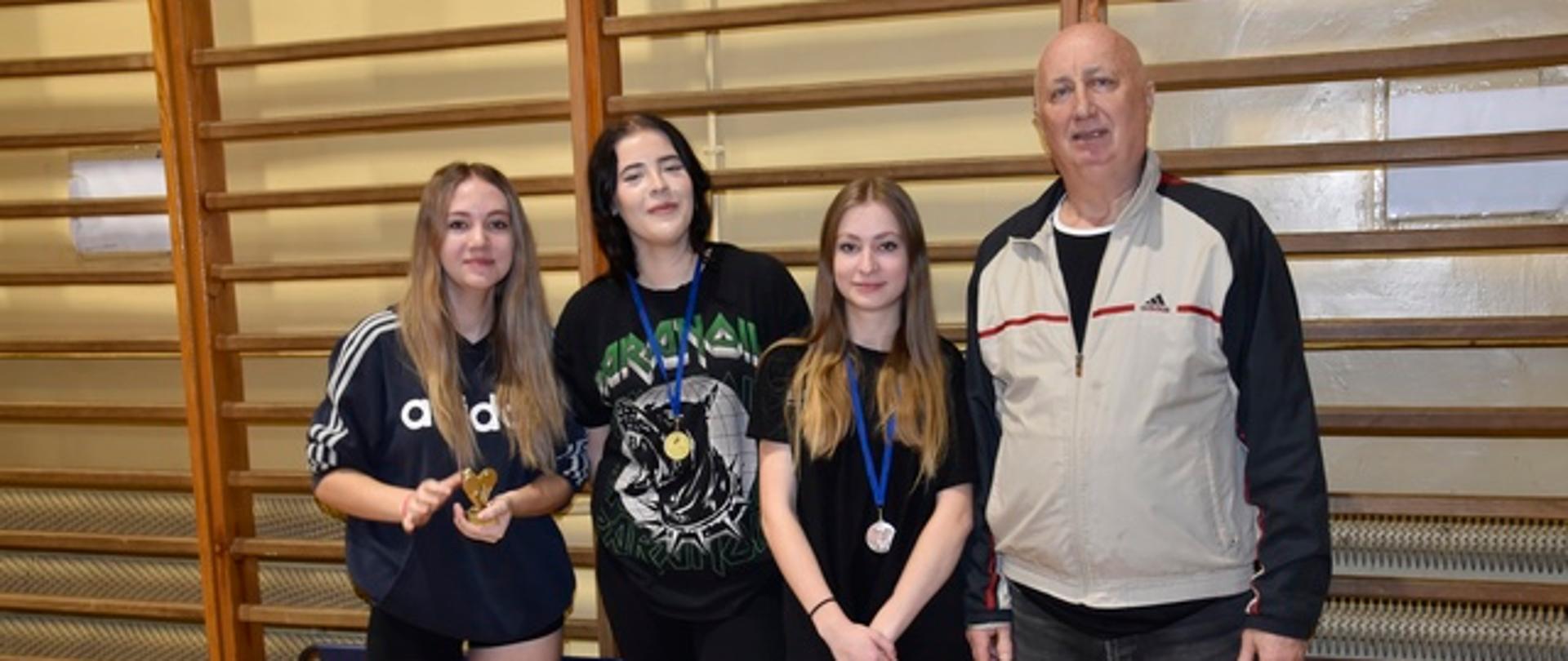 Dekoracja dziewcząt szkół średnich - trzy dziewczyny z medalami stoją z organizatorem