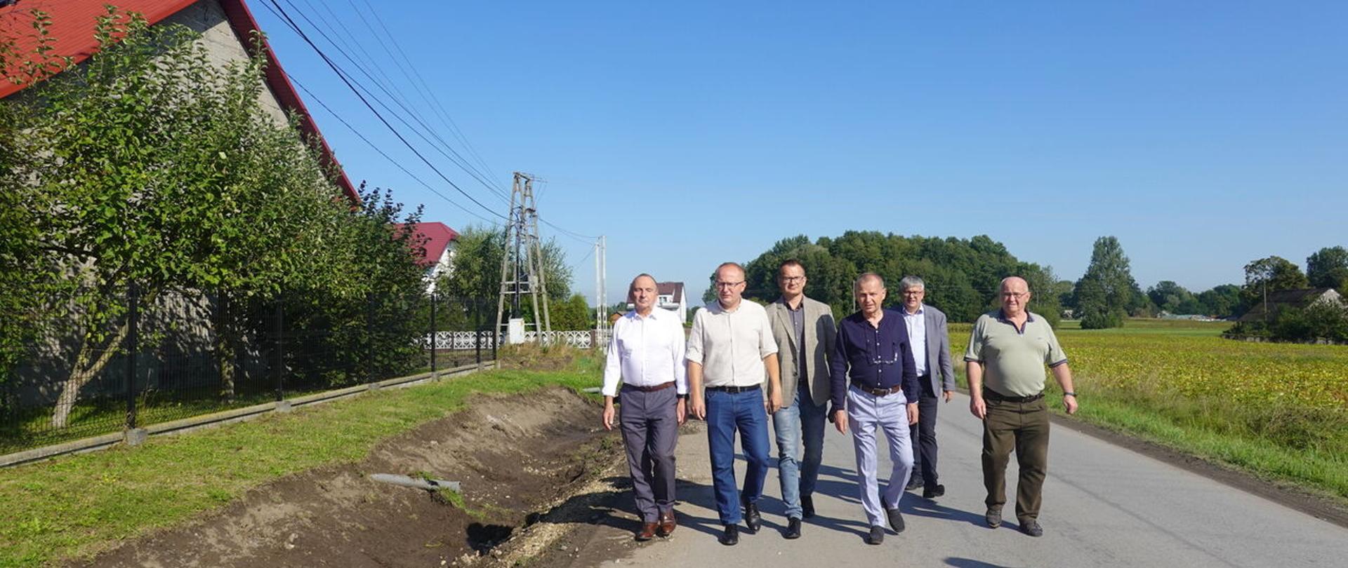 Zdjęciem Przedstawia Skład zarządu powiatu dąbrowskiego idący po drodze