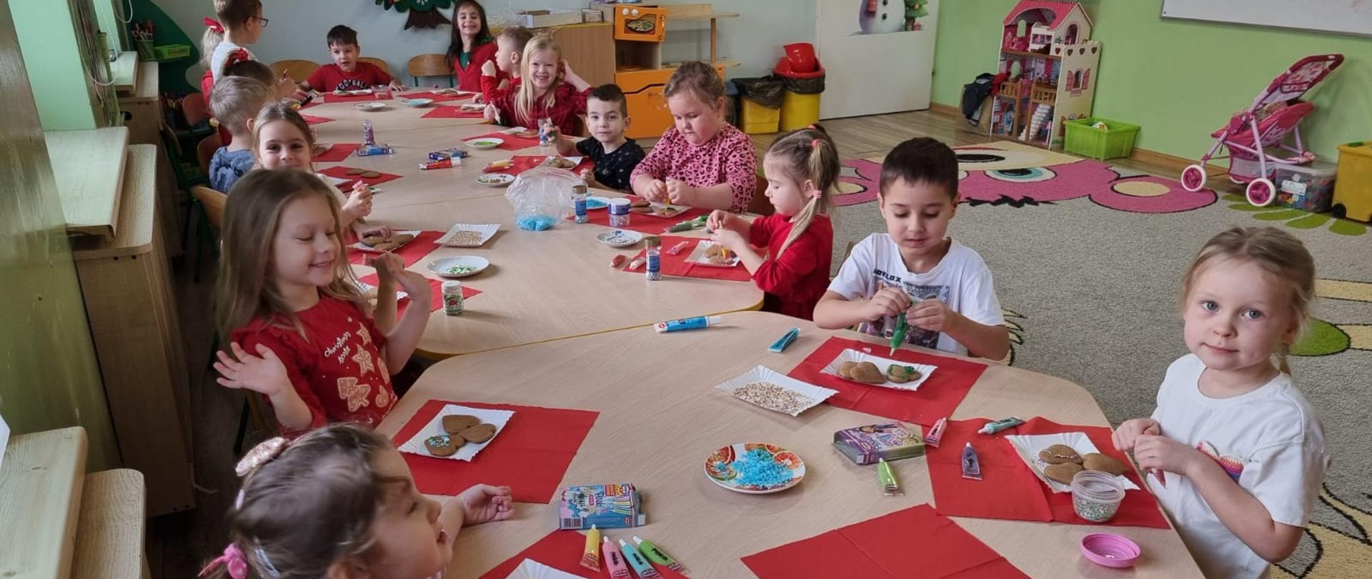 Grupa dzieci zdobi świąteczne pierniki