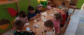 Kreatywne zajęcia artystyczne - dzieci siedzą przy stole, malują wycinanki w kształcie kotów