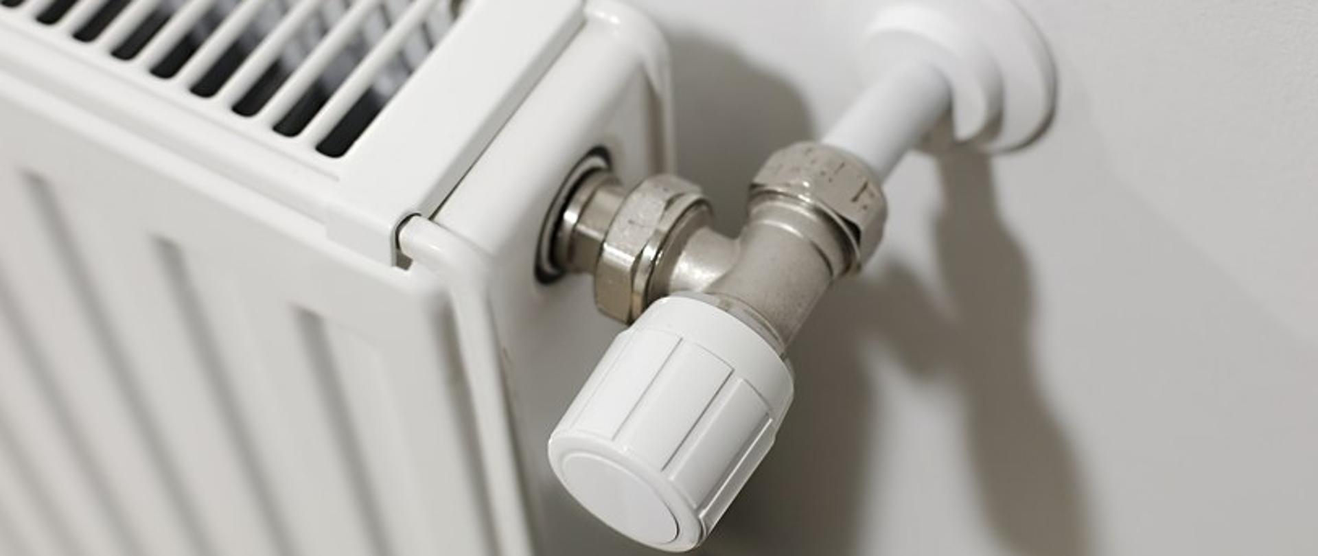 zdjęcie przedstawia biały grzejnik z termostatem 