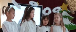 Przedszkolaki odgrywają jasełka w przebraniach świątecznych, w tle szopka