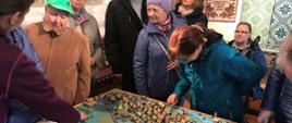 Uczestnicy Koła zwiedzają Galerię - stoją przy makiecie
