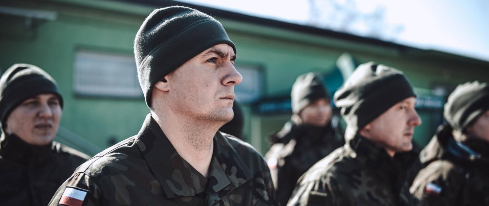 ujęcie twarzy mężczyzn z bliska stojących na zewnątrz w mundurach wojskowych.