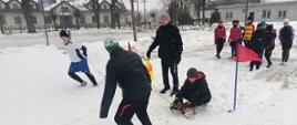 Zabawy na śniegu - dzieci pokonują tor przeszkód w zaprzęgu