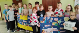Uczniowie stoją w grupie, trzymają w ręku 2 plakaty wykonane w ramach projektu