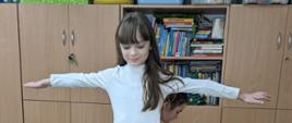 Podczas ćwiczeń z koordynacji ruchowej - dziewczynka maszeruje po ławce
