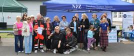 Zdjęcie grupowe przedstawiające uczestników spaceru Nordic Walking. Uczestnicy ze swoimi kijkami w przygotowaniu przed marszem, podczas wydarzenia profilaktyczno-edukacyjnego „Opieka koordynowana w POZ”. 