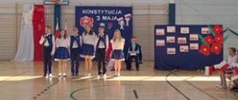 Na pierwszym planie uczniowie klasy IV w trakcie występu na tle dekoracji 
