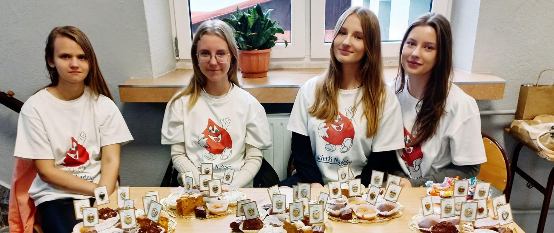 Na zdjęciu cztery wolontariuszki w koszulkach białych z napisem Iskierka Nadziei.