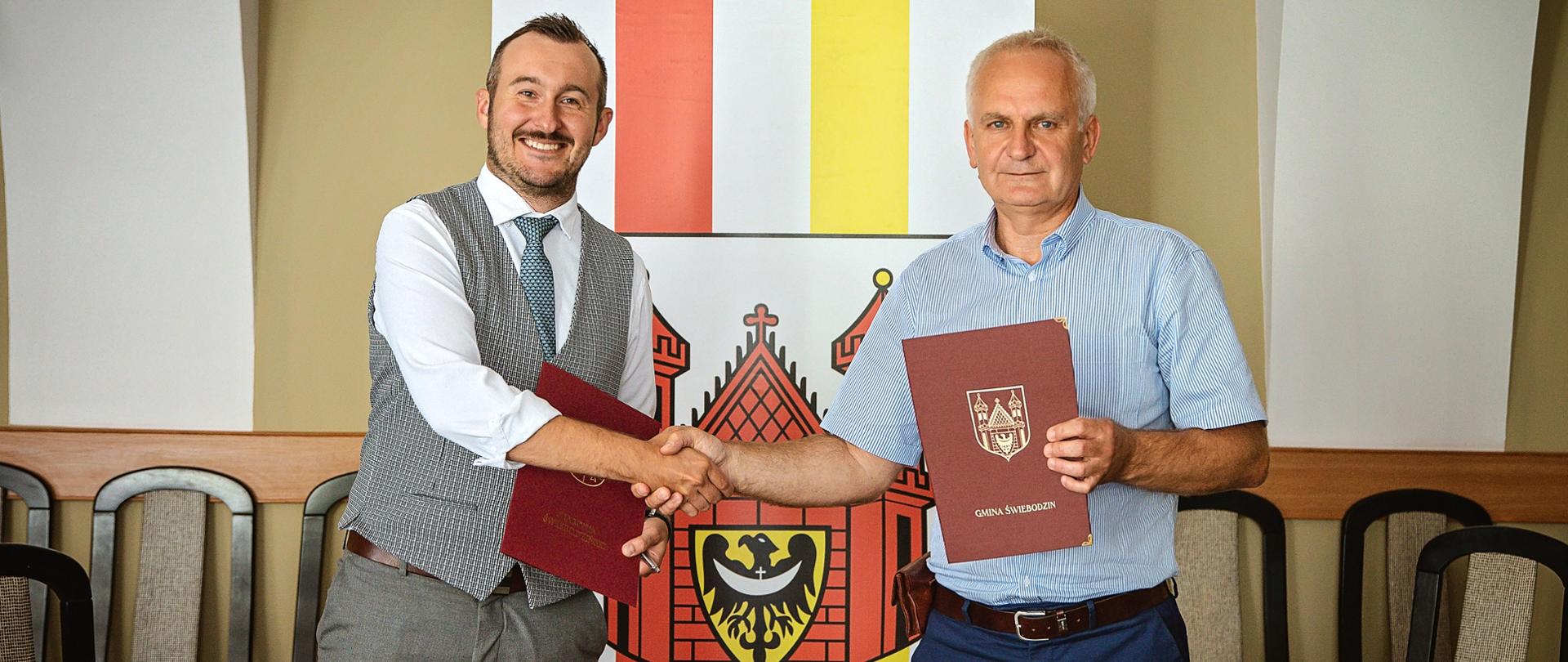 dwaj mężczyźni podpisujący dokumenty