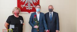 trzy osoby na tle godła