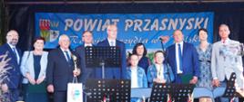 Wręczenie nagród dla najlepszych rolników w powiecie przasnyskim. Na scenie dożynkowej stoją samorządowcy Starosta Przasnyski i Sekretarz Przasnysza oraz Senator Jan Maria Jackowski wraz z nagrodzonymi rolnikami z terenu gminy miejskiej Przasnysz.