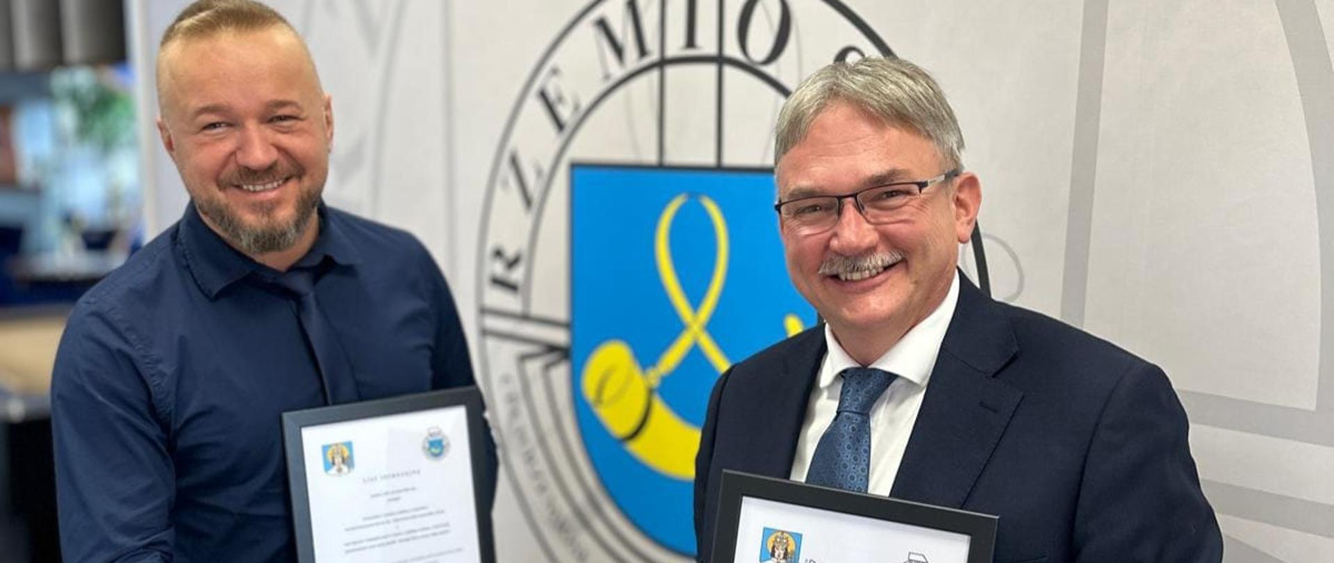 Dwóch mężczyzn trzymając dokumenty podaje sobie rękę 