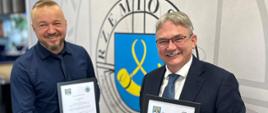 Dwóch mężczyzn trzymając dokumenty podaje sobie rękę 