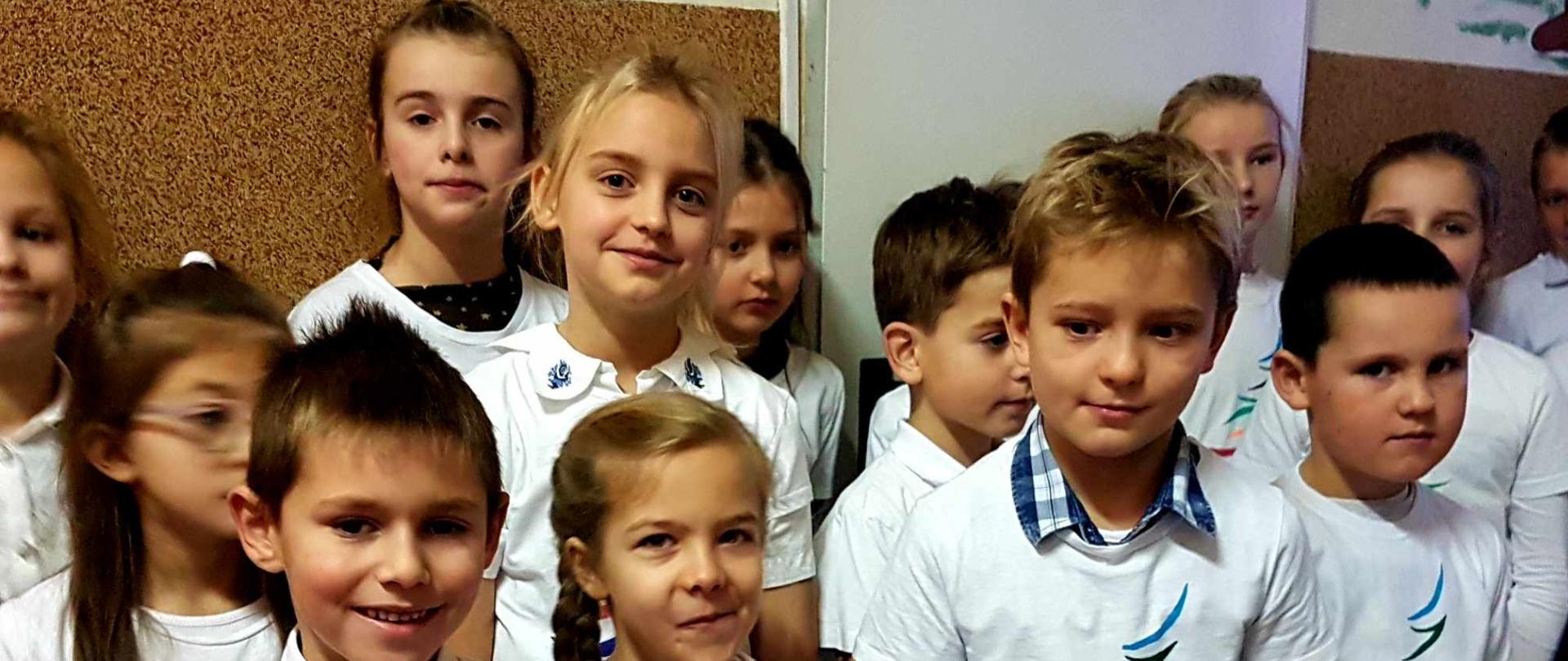 Uczniowie w białych koszulkach z kolorowym logo Gminy Spytkowice.