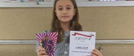 Daria pozuje z nagrodami - pluszowym misiem, dyplomem i statuetką
