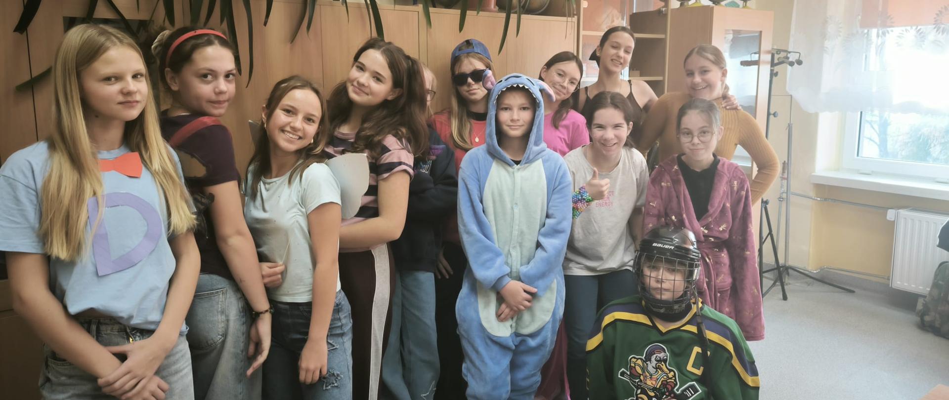 Uśmiechnięta grupa dzieci pozuje do zdjęcia w tle szafy i okno w pomieszczeniu