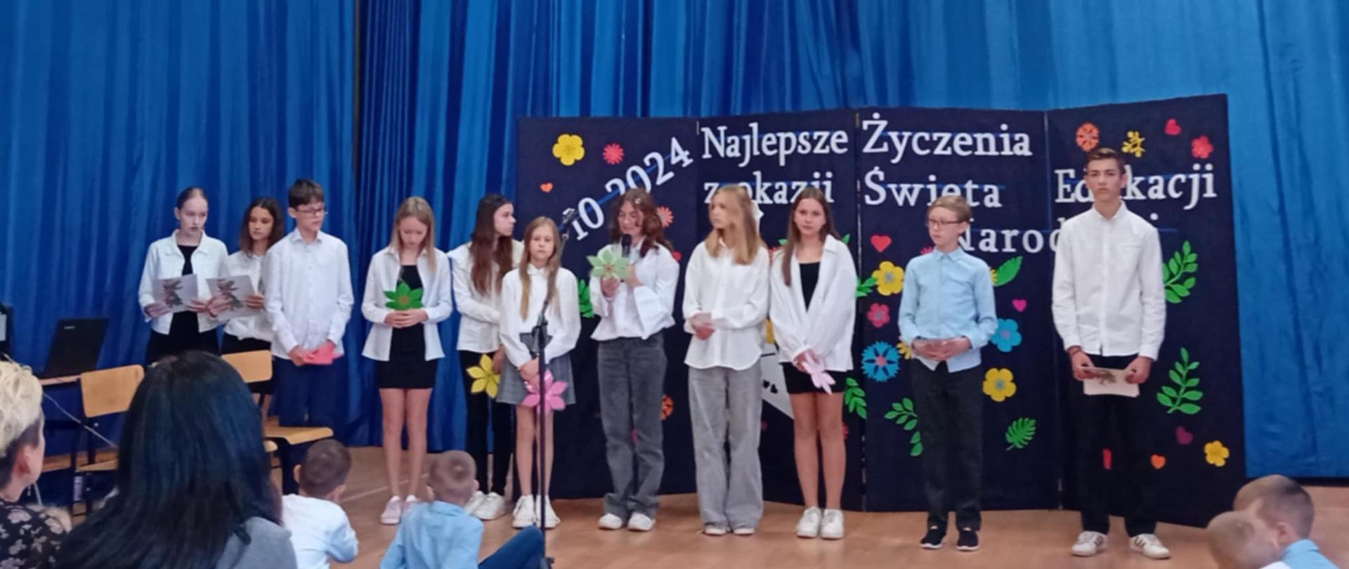 Grupa młodzieży ustawiona w rzędzie obok siebie. Ubrani w białe koszule. 