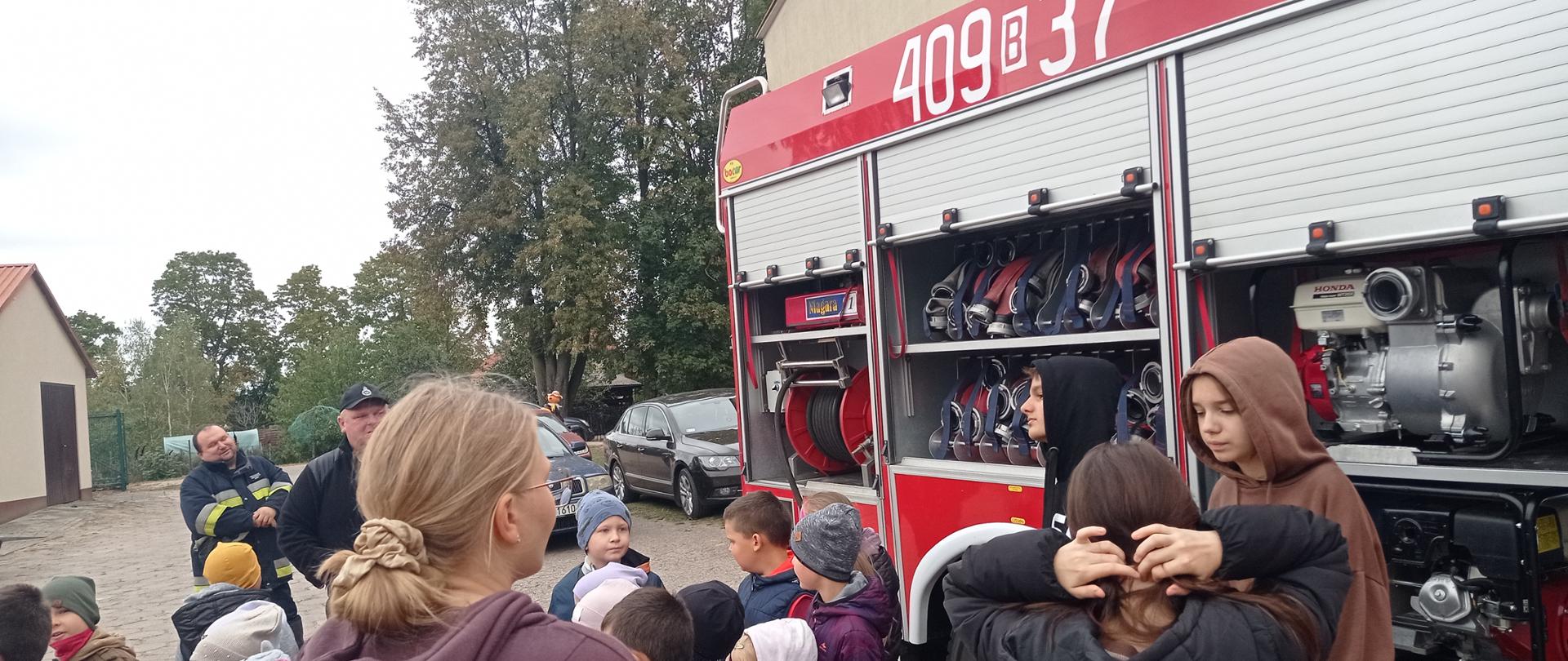 Uczniowie stoją obok wozu strażackiego.