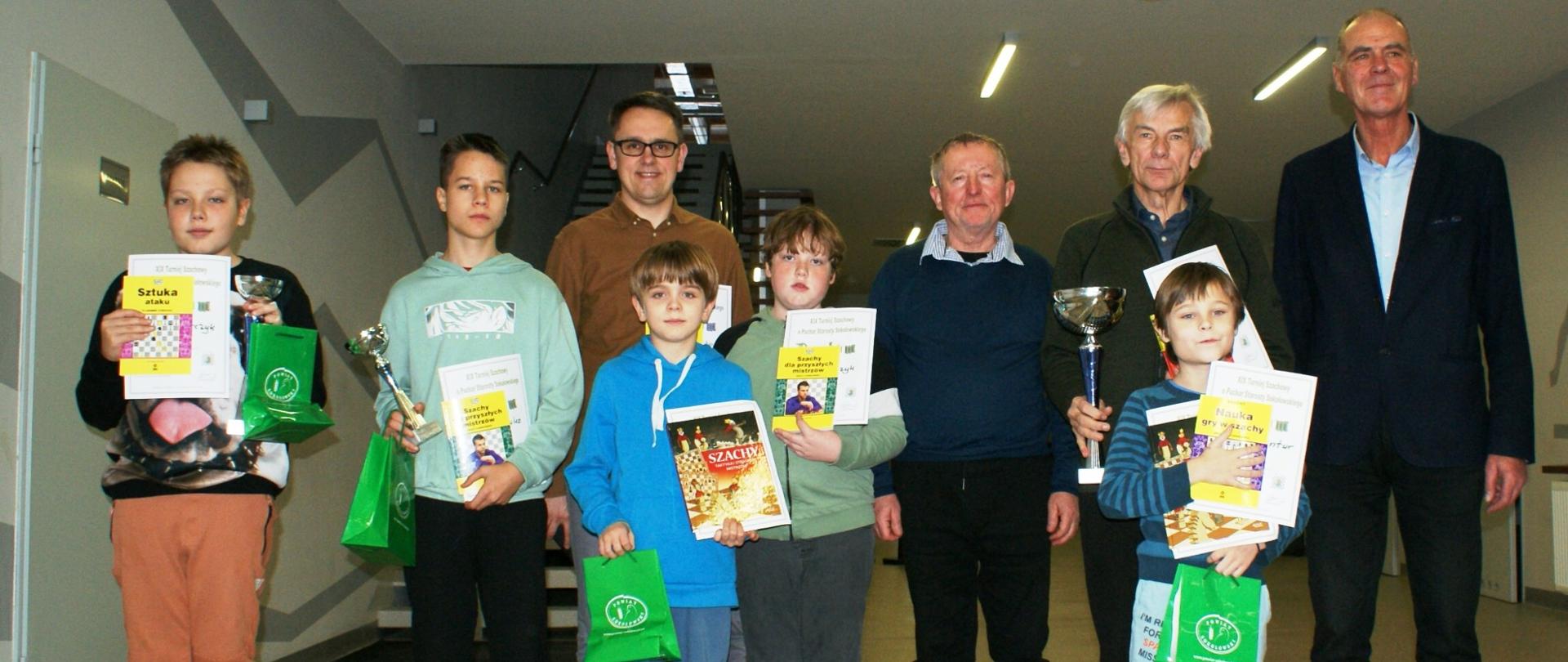 Zdjęcie grupowe uczestników turnieju wraz z organizatorami i wicestarostą.
Uczestnicy trzymają w rękach nagrody, dyplomy oraz puchary.