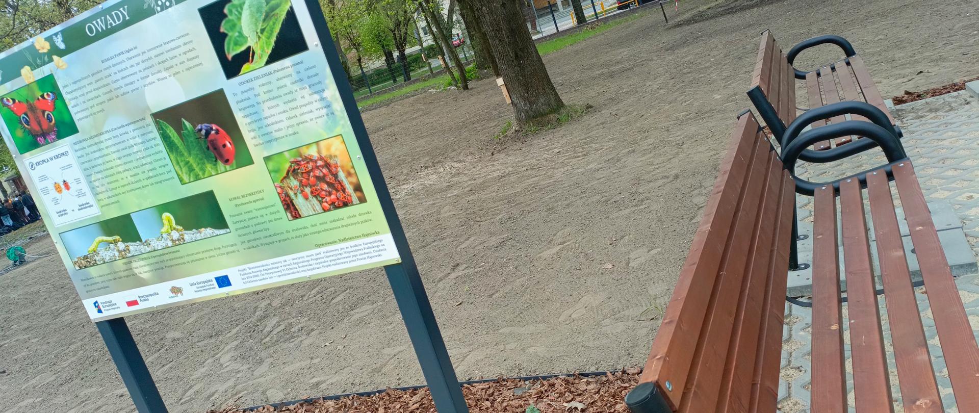 Tablica edukacyjna stoi obok ławek