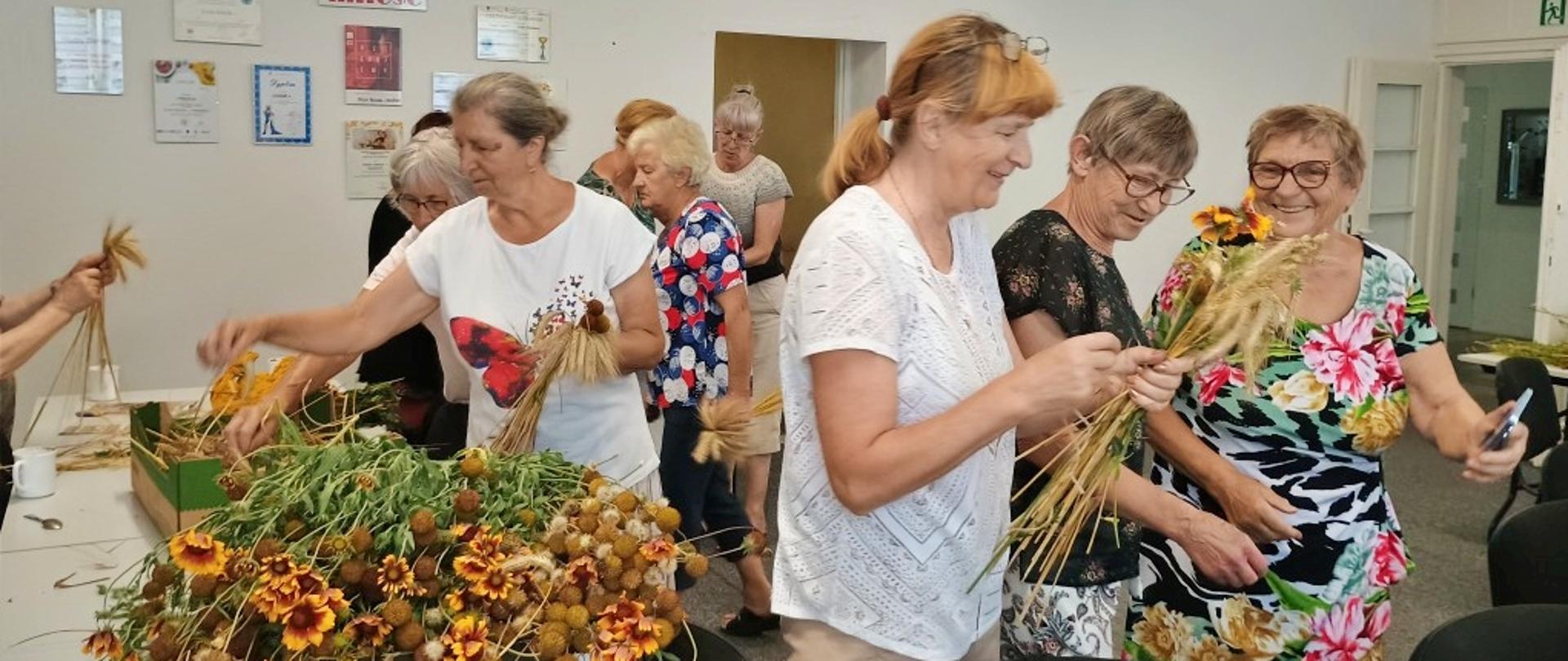 seniorzy podczas warsztatów układania bukietów z suszonych roślin