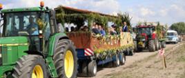Pojazdy rolnicze z udekorowanymi przyczepami, na przyczepach goście dożynkowi