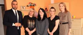 Wicestarosta Polkowicki, Dyrektor Powiatowego Centrum Pomocy Rodzinie oraz wolontariuszki stoją w salonie w mieszkaniu 