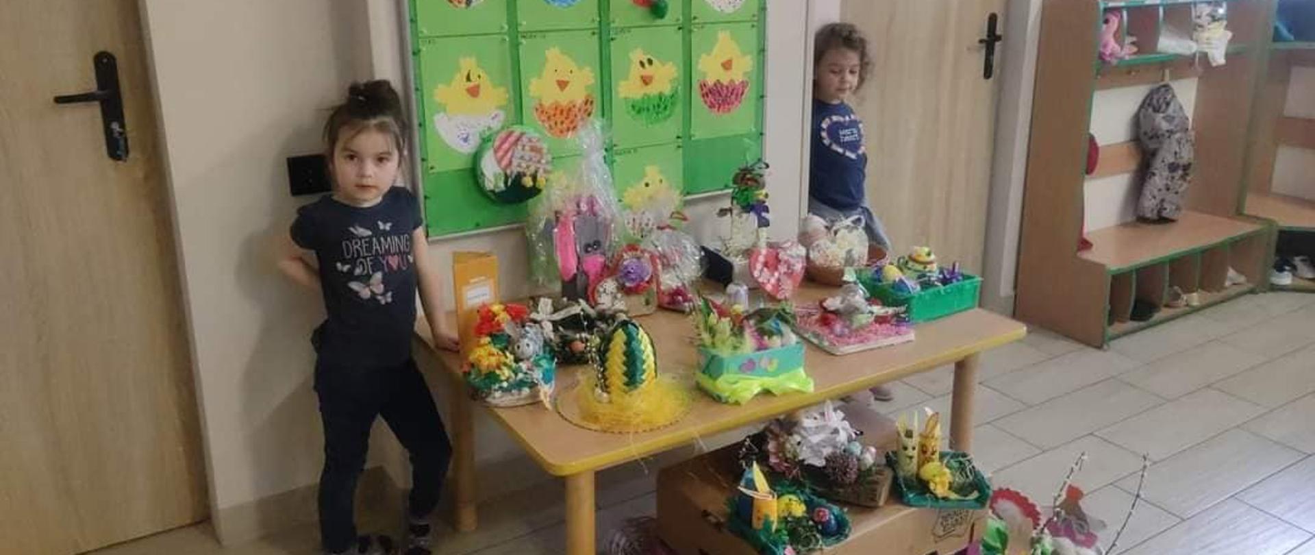 2 dziewczynki przy stole ze stroikami Wielkanocnymi
