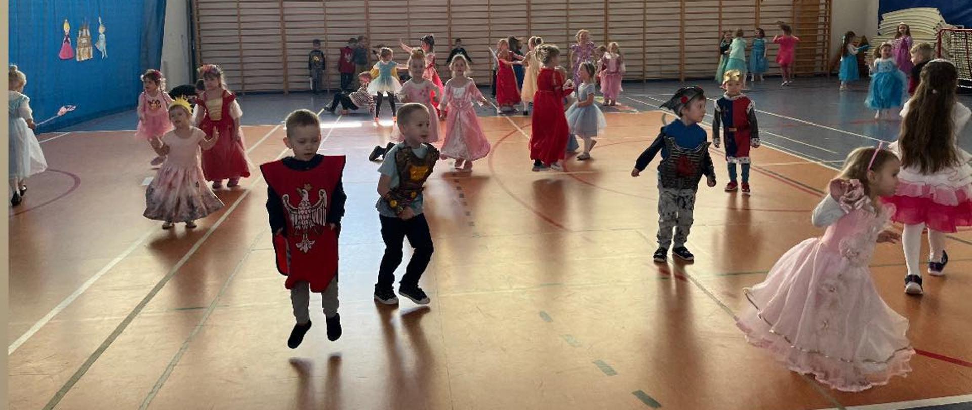 U góry dziewczynka w czerwonej szacie tańczy z dziewczynka w koronie i biało różowej sukience w tle bawią się dzieci.
Na dole dzieci bawią się na sali gimnastycznej.