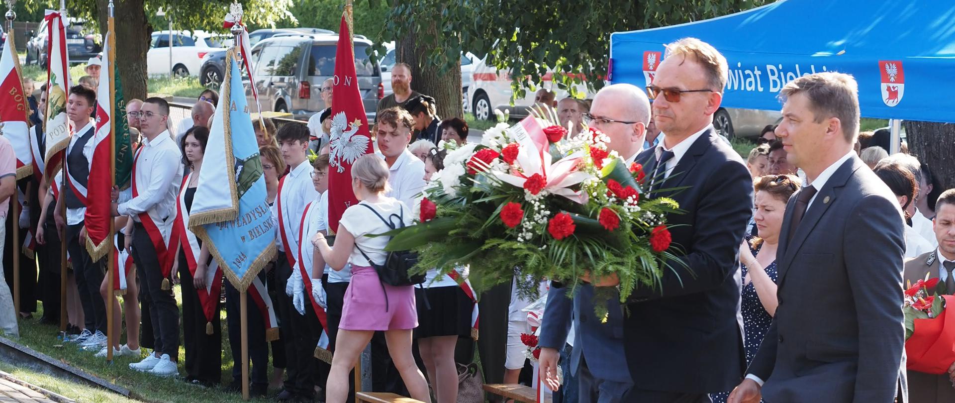 Wicestarosta bielski Piotr Bożko, członek zarządu powiatu Maciej Bobel oraz sekretarz powiatu Marek Martyniuk składają wiązankę na mogiłach ofiar zbrodni pilickiej