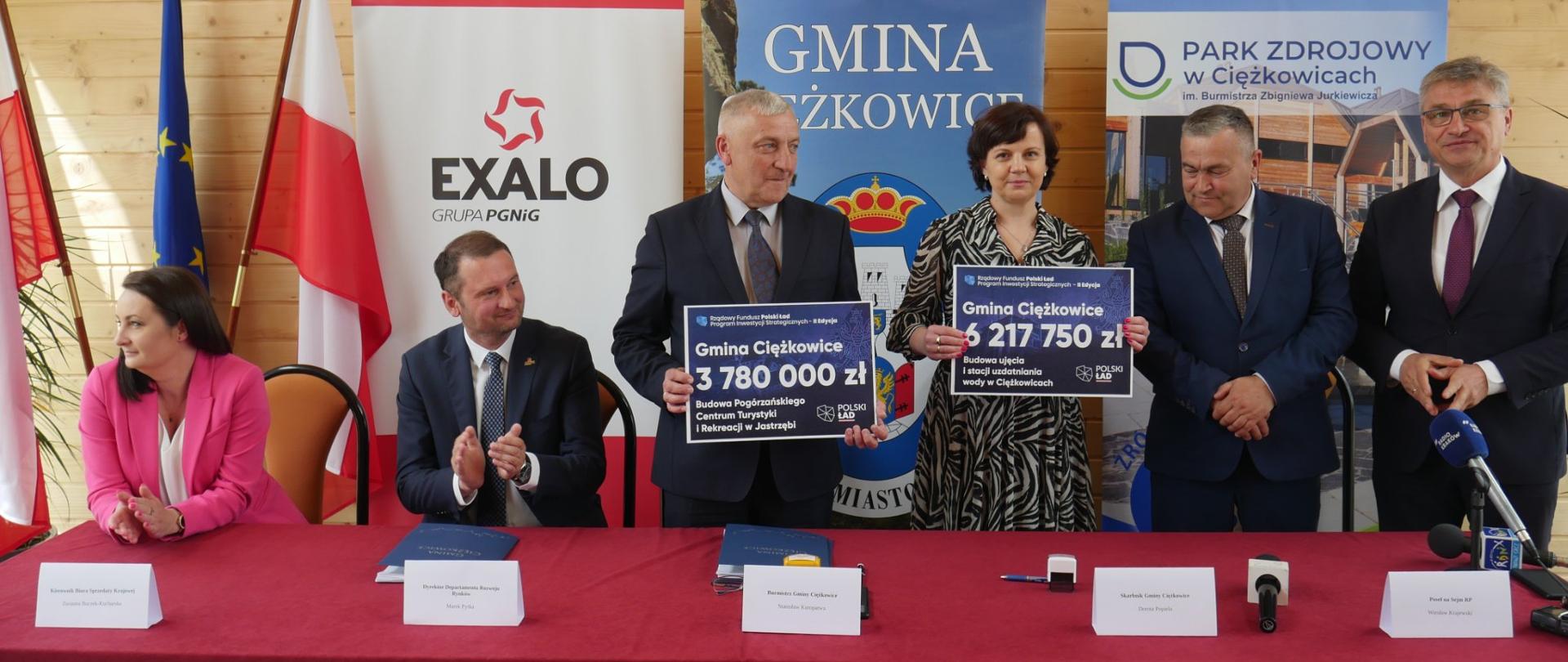 Zdjęcie przedstawia wręczenie czeków do rąk Burmistrza oraz Skarbnik Gminy Ciężkowice